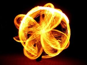 Fire performer creating a glowing flower-shaped pattern, symbolizing how intention shapes the flow of your life.